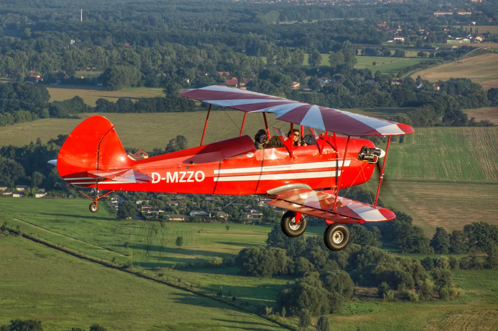 Roter Doppeldecker mit offenem Cockpit im Flug