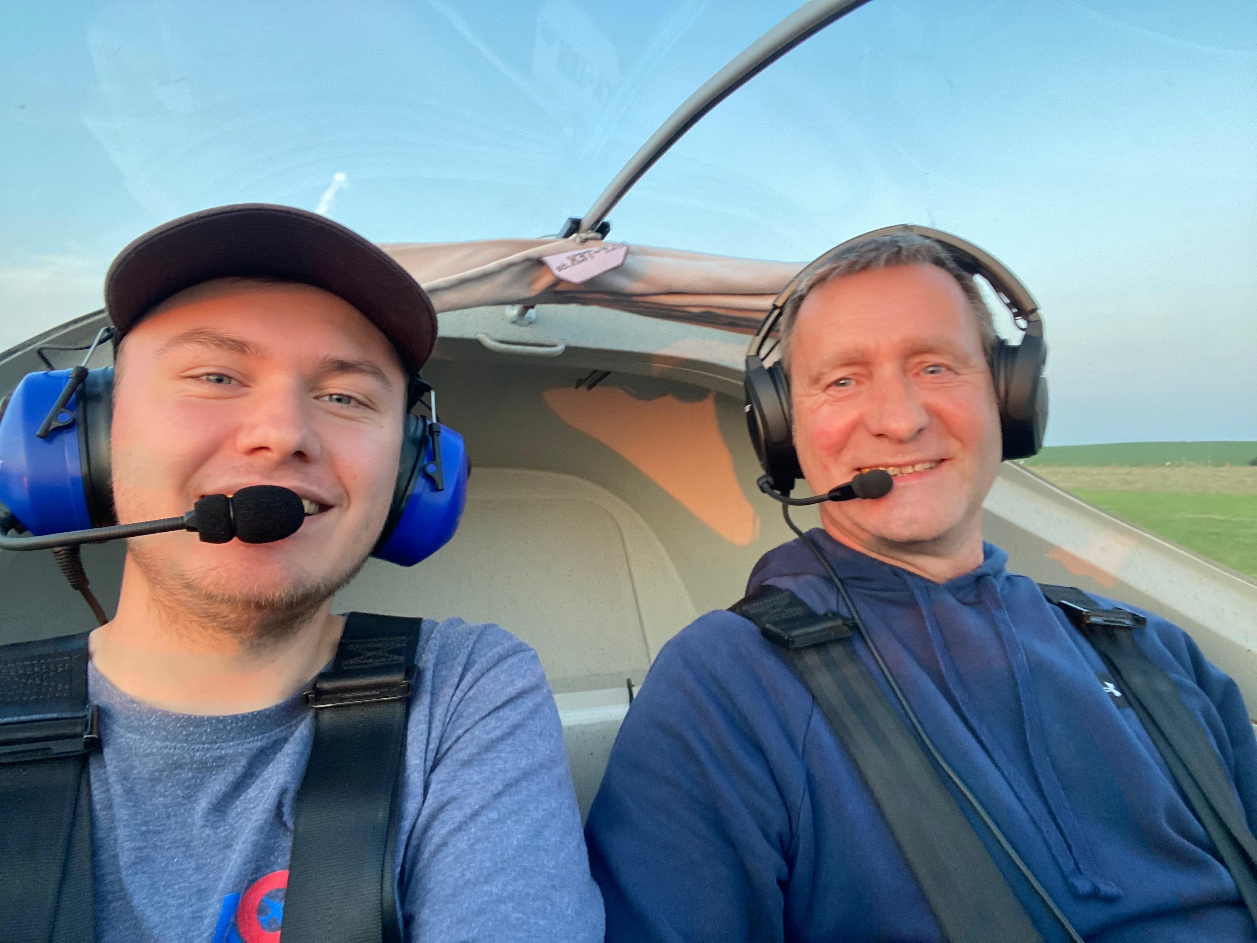 Zwei Männer tragen Headsets im Cockpit eines Flugzeugs, während sie Selfie machen