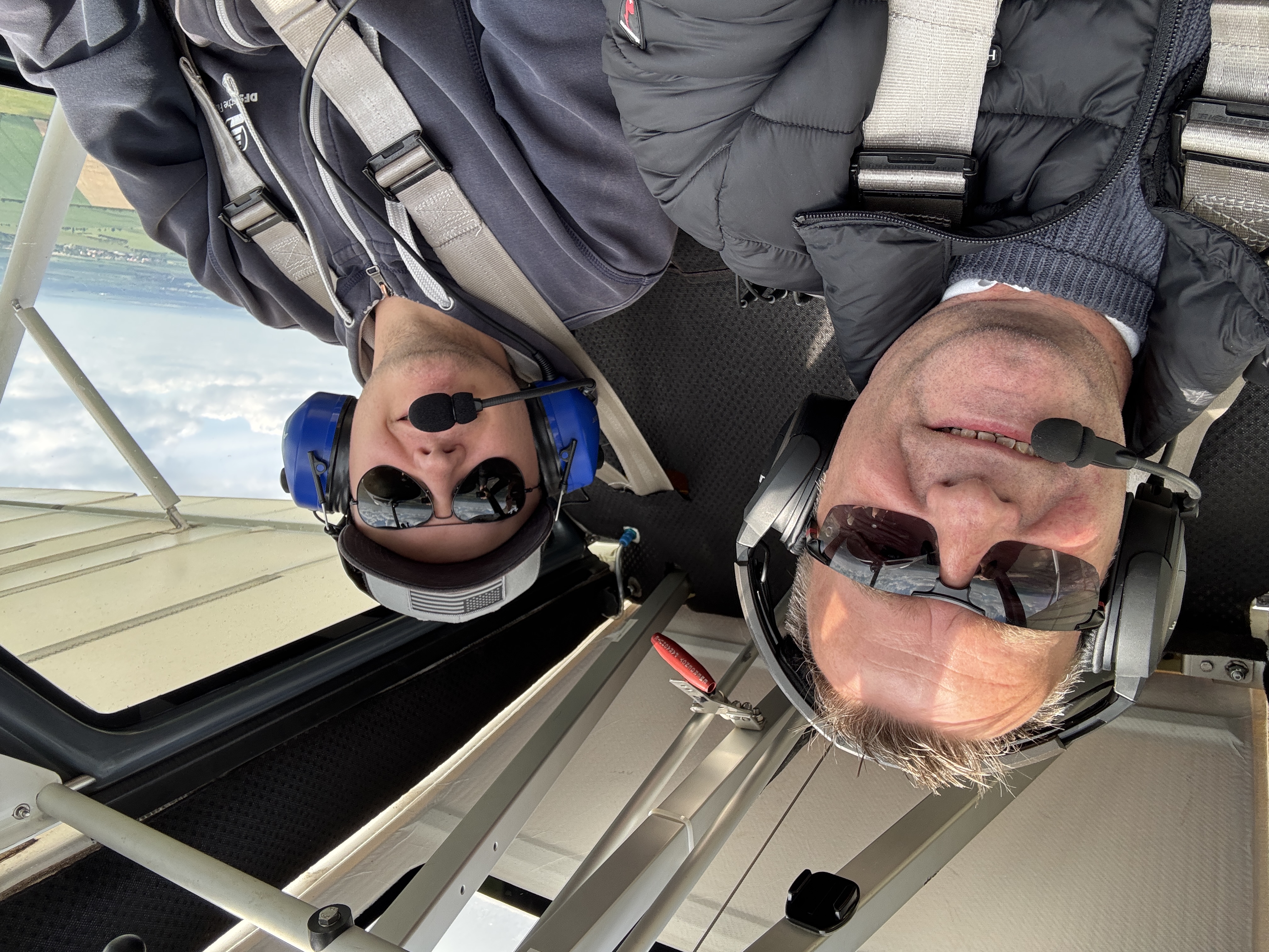 Zwei Männer tragen Headsets und sitzen zusammen im Cockpit eines kleinen Flugzeugs, bereit zum Flug.