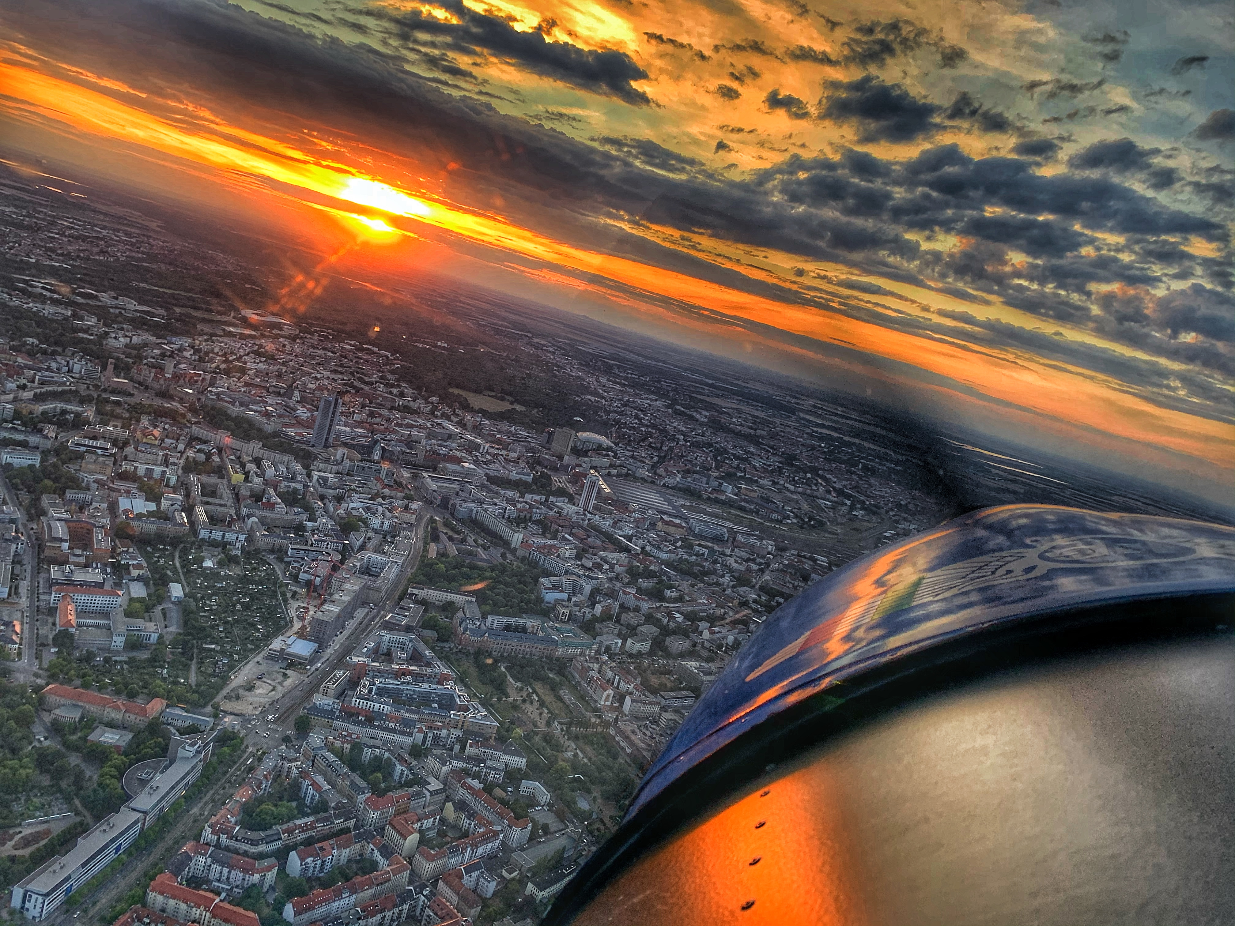 Blick aus einem Flugzeugfenster auf eine Stadtlandschaft bei Sonnenuntergang